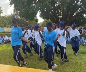 group of girls in white and blue shirts dancing and smiling